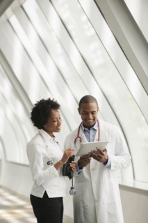 Doctors using digital tablet in hospital corridor