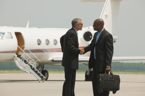 Businessmen shaking hands on airport tarmac