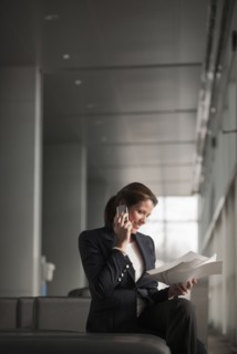 Caucasian businesswoman holding paperwork and talking on cell phone