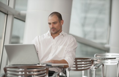 Caucasian man using laptop in cafe