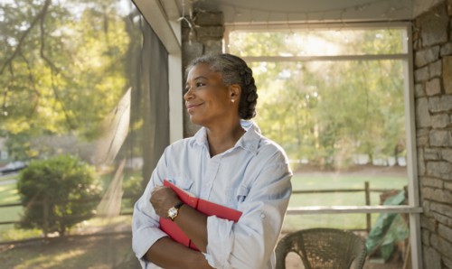 Mixed race woman holding book on porch