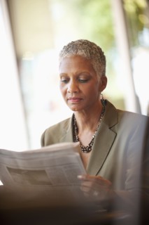 African American businesswoman reading newspaper in cafe