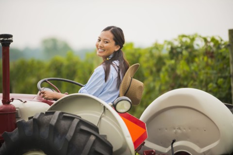 Asian woman driving tractor in field