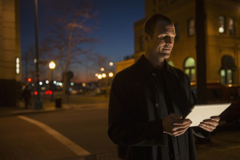 Caucasian man using tablet computer on city street