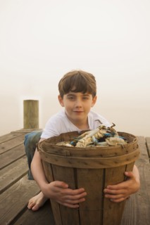 Caucasian boy holding basket of crabs
