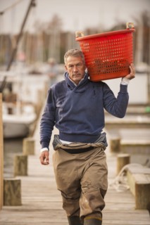 Caucasian fisherman carrying basket on dock