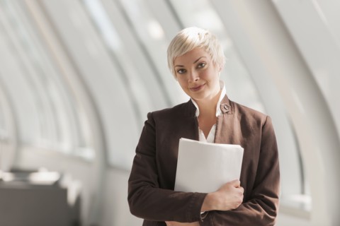 Caucasian businesswoman carrying papers in lobby