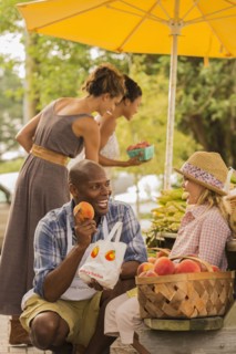 Vendor showing produce to girl at farmers market