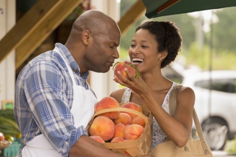 African American people smelling produce at farmers market