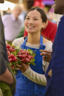Clerk holding produce at farmers market