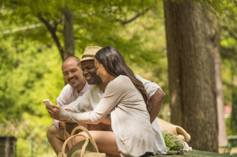 Friends using cell phone on picnic table