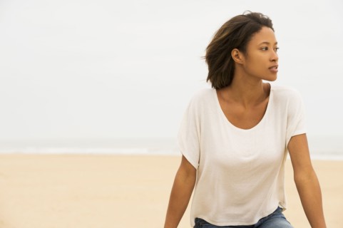 Pensive African American woman sitting at beach
