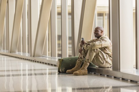 African American soldier using cell phone in airport