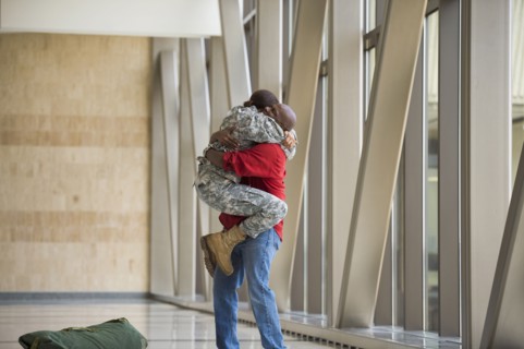 African American soldier hugging husband in airport