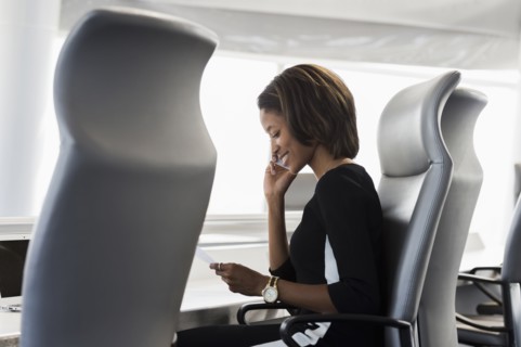 Black businesswoman reading paperwork talking on cell phone