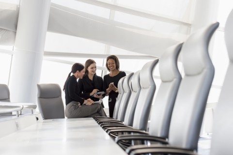 Businesswomen using cell phone in conference room