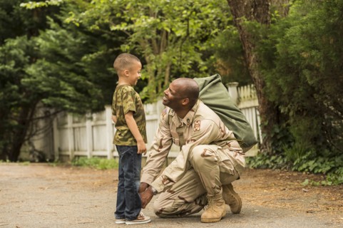 African American soldier tying shoelace for son