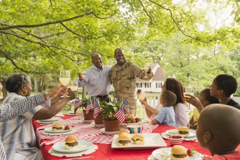 Soldier and multi-generation family toasting with lemonade at picnic