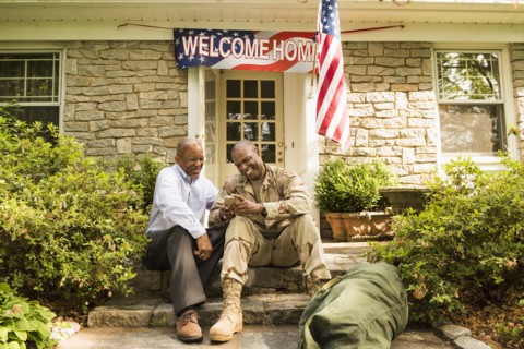 Soldier and father sitting on front stoop texting on cell phone