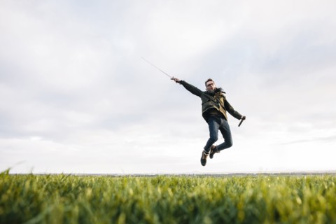 Caucasian man unsheathing sword in field