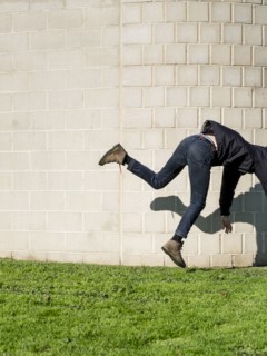 Caucasian man falling near brick wall