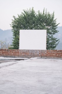 Blank board on brick wall near tree