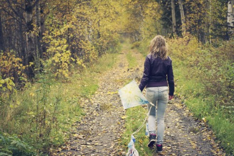 Woman carrying kite on dirt path