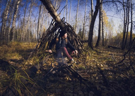 Man sitting in wooden shelter in forest