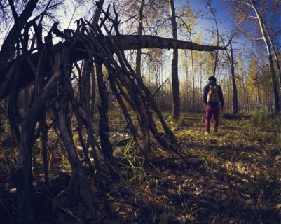 Man standing near wooden shelter in forest