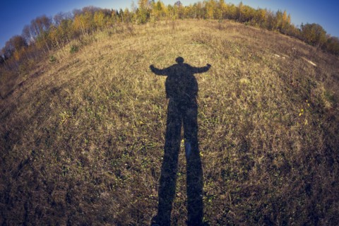 Fish-eye lens view of shadow of man in field