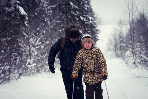 Caucasian father and daughter cross-country skiing on snowy road