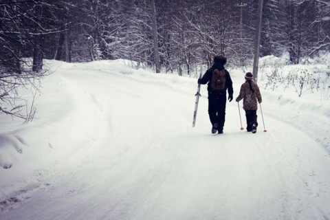 Caucasian father and daughter cross-country skiing on snowy road