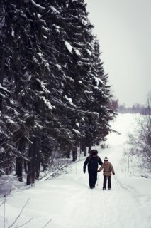 Caucasian father and daughter cross-country skiing on snowy road