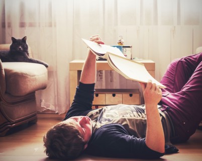Caucasian man reading on living room floor