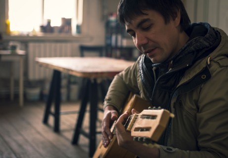Asian man playing guitar in living room