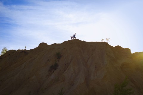 People standing on hilltop under blue sky