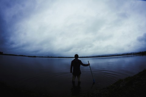 Caucasian man standing in still remote lake