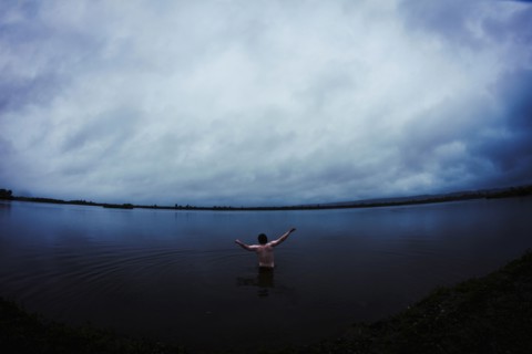 Caucasian man standing in still remote lake