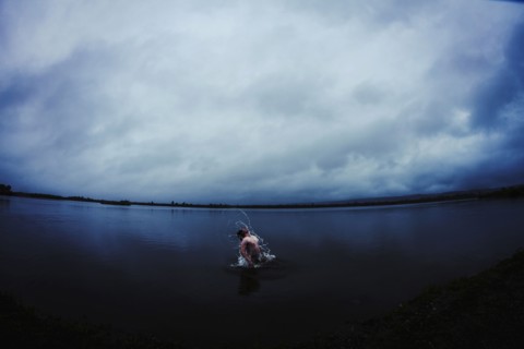 Caucasian man splashing in still remote lake
