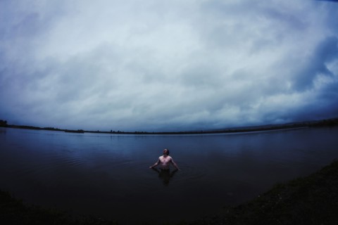 Caucasian man standing in still remote lake