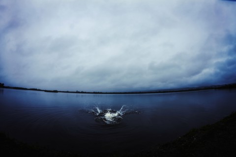 Caucasian man splashing in still remote lake