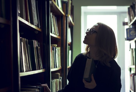 Caucasian woman searching for book in library