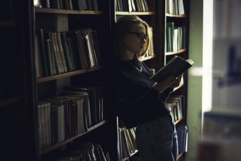 Caucasian woman reading book in library