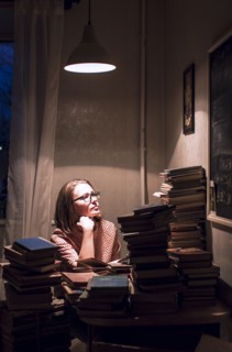 Caucasian woman sitting at stack of books