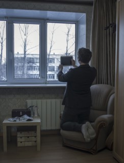 Caucasian man photographing with digital tablet in living room