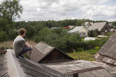 Caucasian man sitting on roof holding book