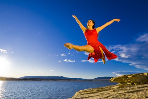 Hispanic woman dancing near lake
