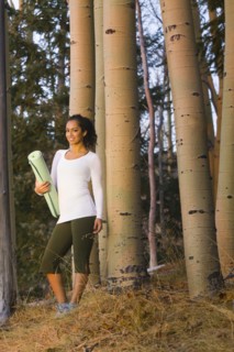 Mixed race woman holding yoga mat in forest