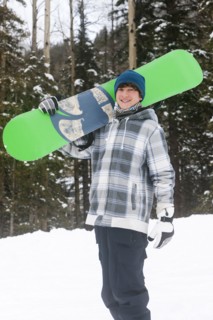 Mixed race snowboarder carrying snowboard