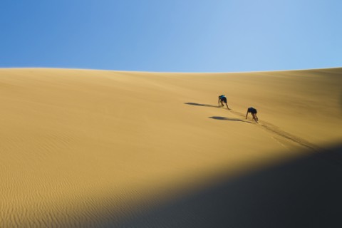 Hispanic couple climbing sand dune